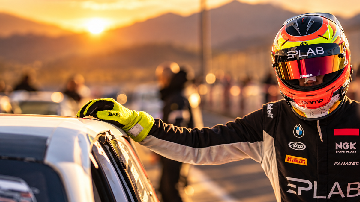 Racing driver wearing EPLAB-branded racing gear at sunset